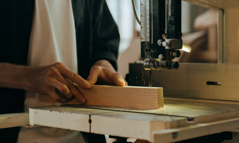 Picture someone cutting a piece of wood with a power saw. Photo by cottonbro from Pexels.
